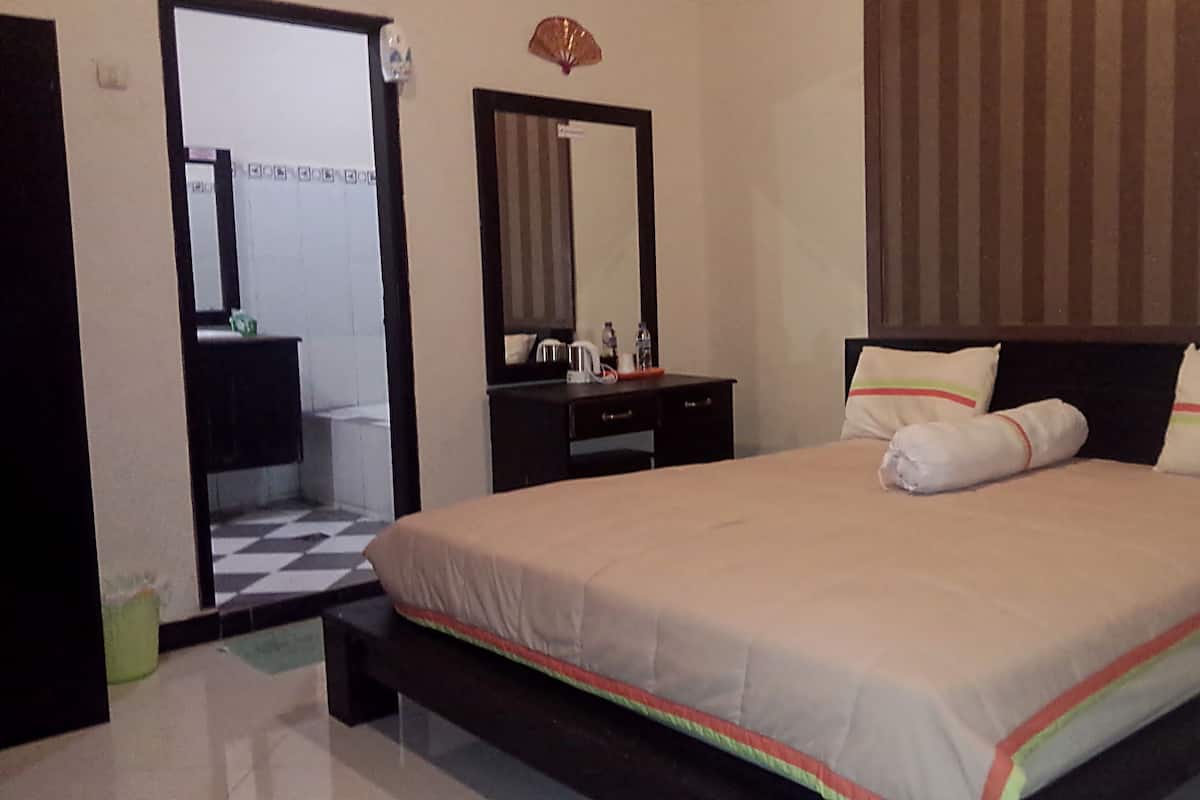 A bedroom with a bed, a dresser, a mirror, and a small table with toiletries.