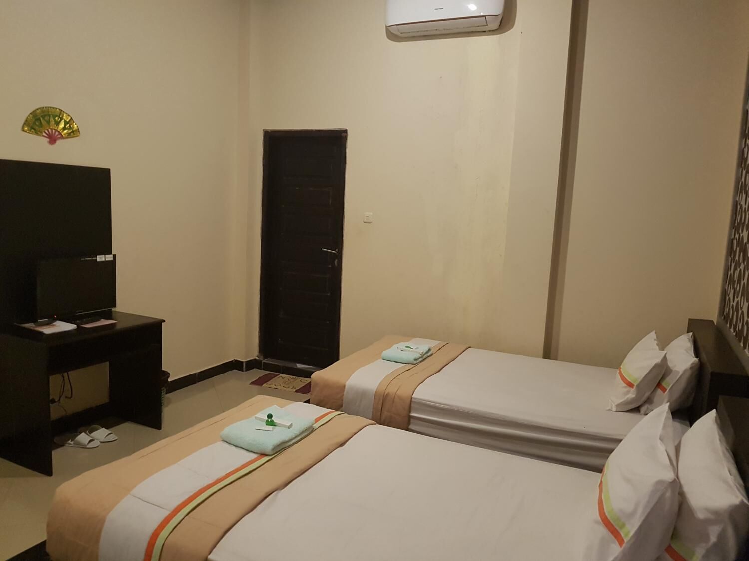 A hotel room with two beds, a TV, a desk, and a door.