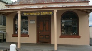 A building with a sign reading "Tenterfield Saddler". It has a wooden door, two large windows, and a corrugated metal roof. - Royal Motel Tenterfield (Tenterfield)