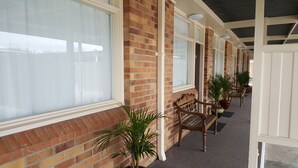 A covered corridor with brick walls, large windows, and potted plants. - Royal Motel Tenterfield (Tenterfield)