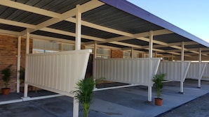 A covered outdoor area with a brick wall, white railings, and potted plants. - Royal Motel Tenterfield (Tenterfield)