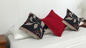 A neatly made bed with a white bedspread and two decorative pillows, one with a floral pattern and the other red. - Royal Motel Tenterfield (Tenterfield)