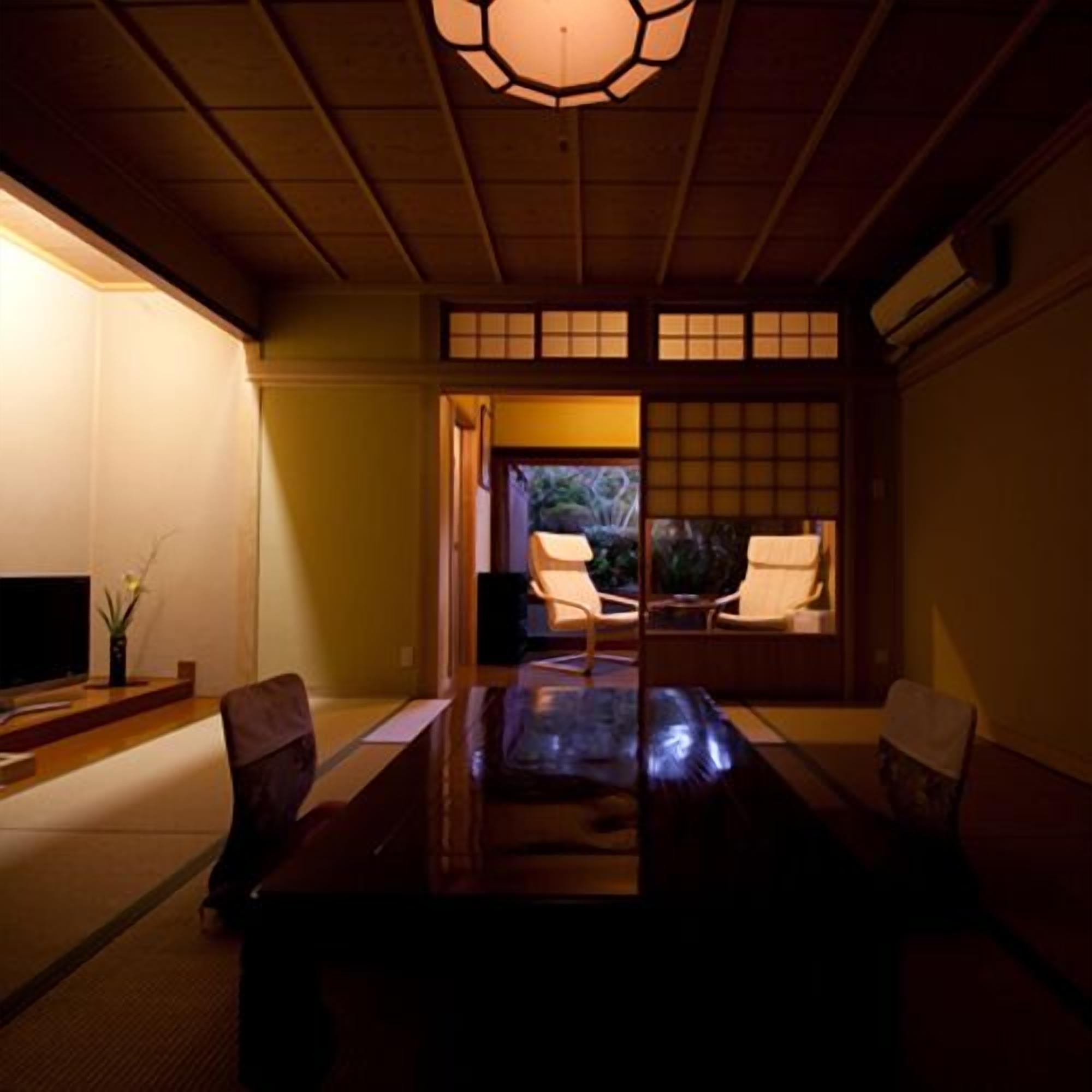 A traditional Japanese room with tatami flooring, a low table, and sliding doors leading to a garden.