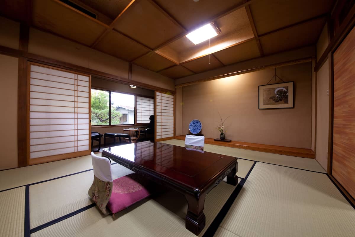A traditional Japanese room with tatami flooring, a low wooden table, and shoji screens.