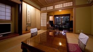 A traditional Japanese room with tatami flooring, a low table, and a television. - Ryokan Sennari (Beppu)