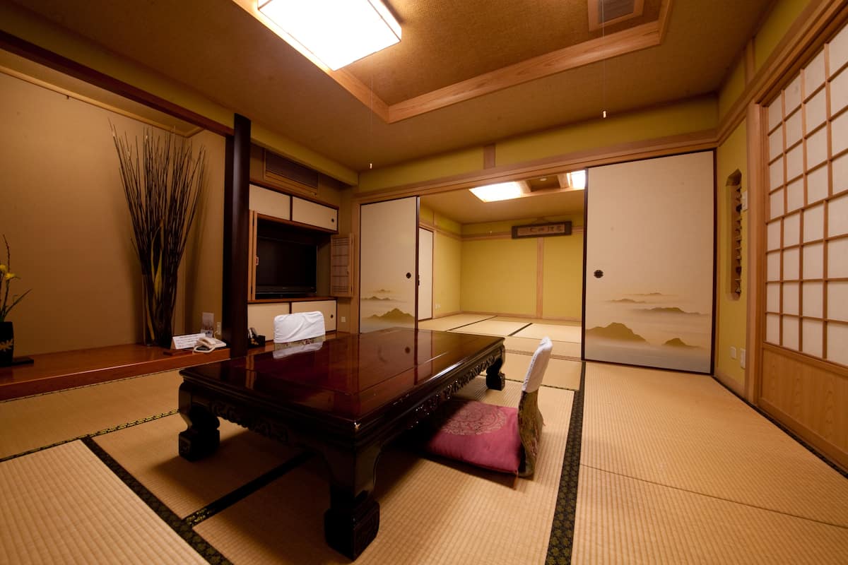A traditional Japanese room with tatami flooring, a low wooden table, and sliding doors with a mountain view.