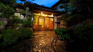 A traditional Japanese building with a stone pathway leading to a wooden gate. - Ryokan Sennari (Beppu)