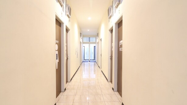 Un pasillo de hotel con puertas que indican los tipos de habitación, señalizadas como “DRM 1” y “BED”.