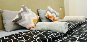 Un lit bien fait, avec une literie à motifs et des coussins décoratifs.