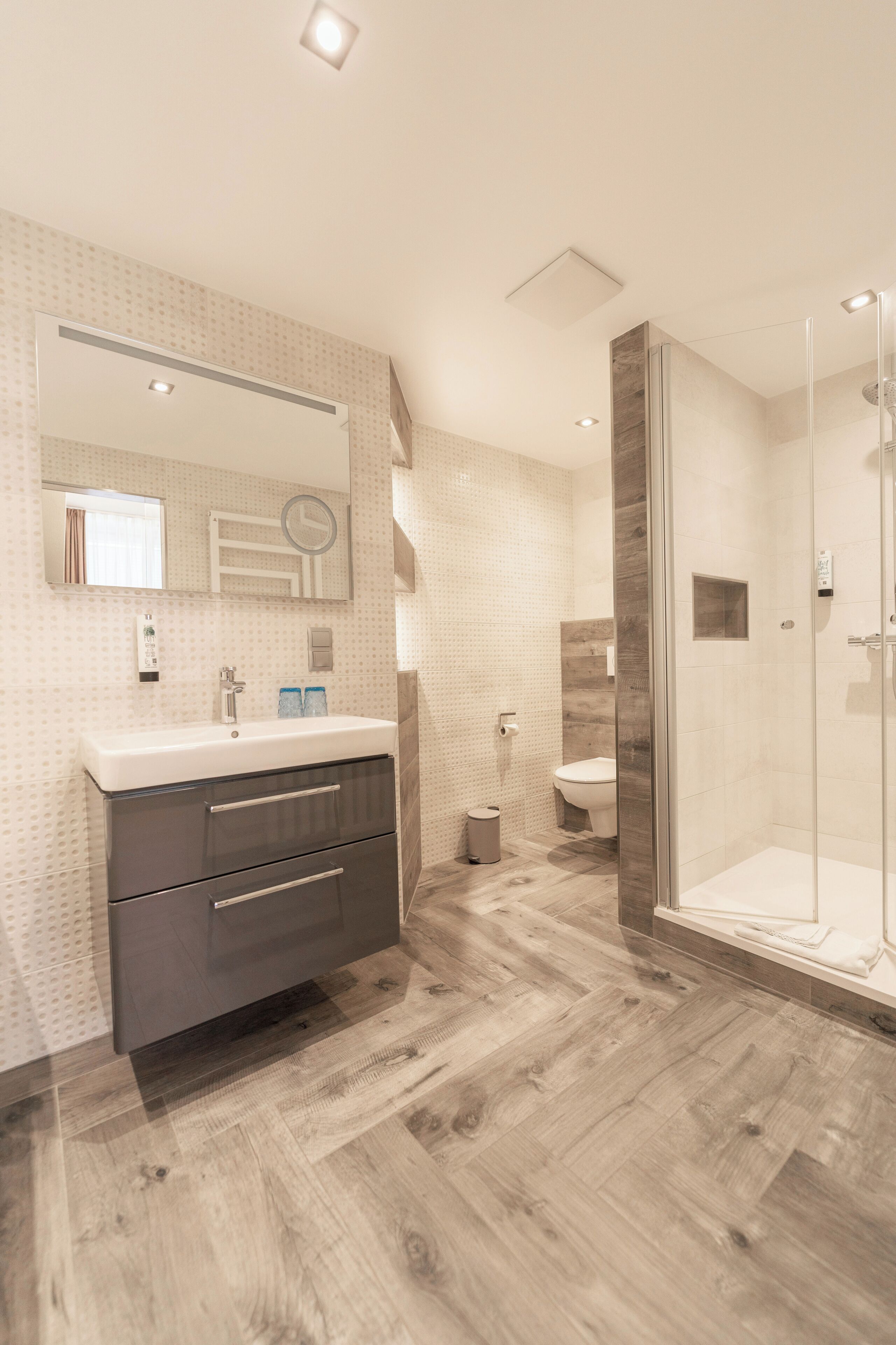 A modern bathroom with a vanity, mirror, and shower.