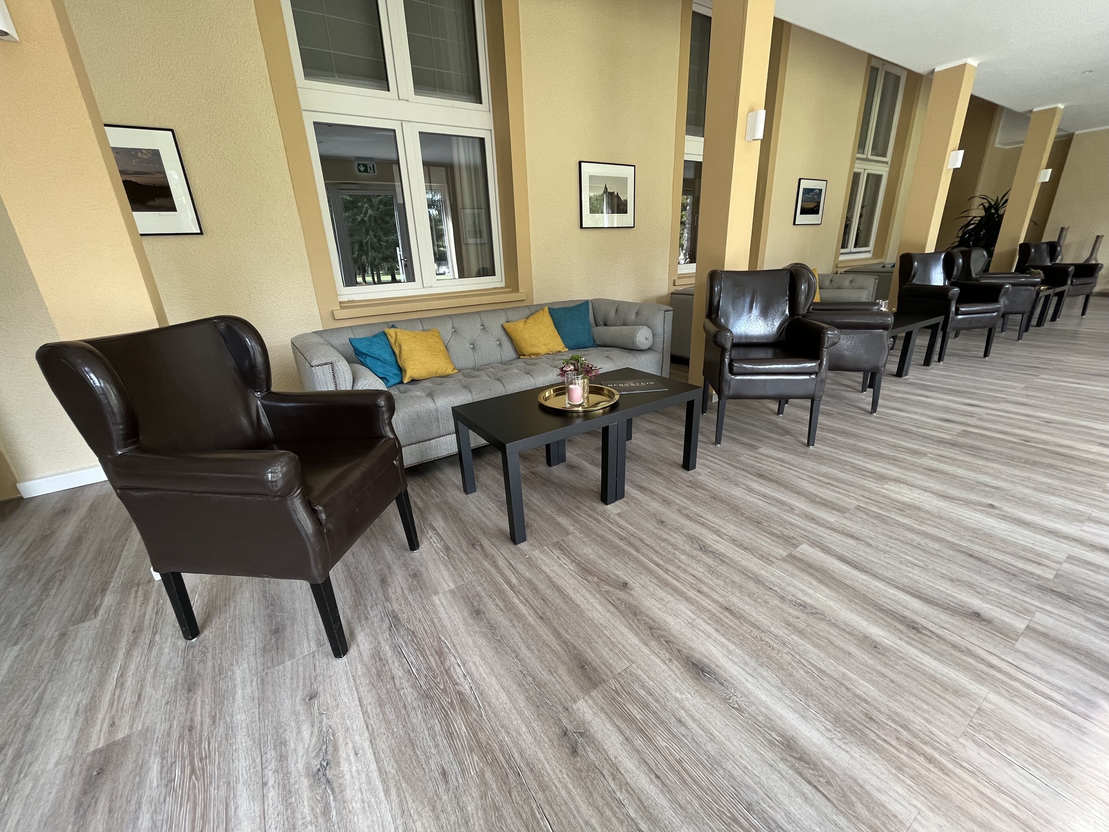 Un vaste espace de vie comprenant un canapé gris, plusieurs fauteuils en cuir et une table basse.