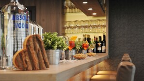 A bar area with a bottle of Absolut Vodka, glasses, and a plant on the counter. - Bernstein Acamed Resort (Nienburg)