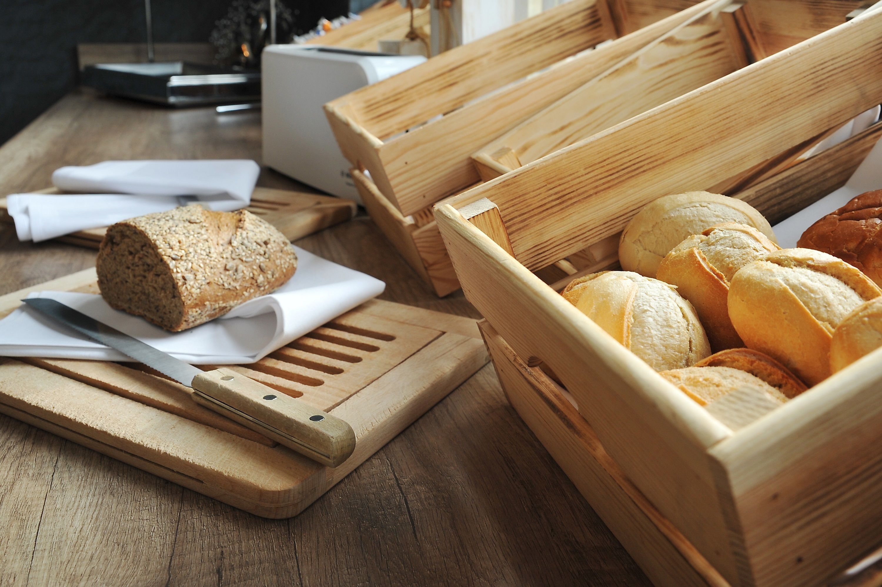 A wooden cutting board with a knife and a loaf of bread on it.