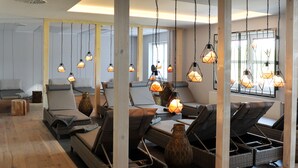 A spa area with multiple massage chairs, wooden floors, and hanging pendant lights. - Bernstein Acamed Resort (Nienburg)