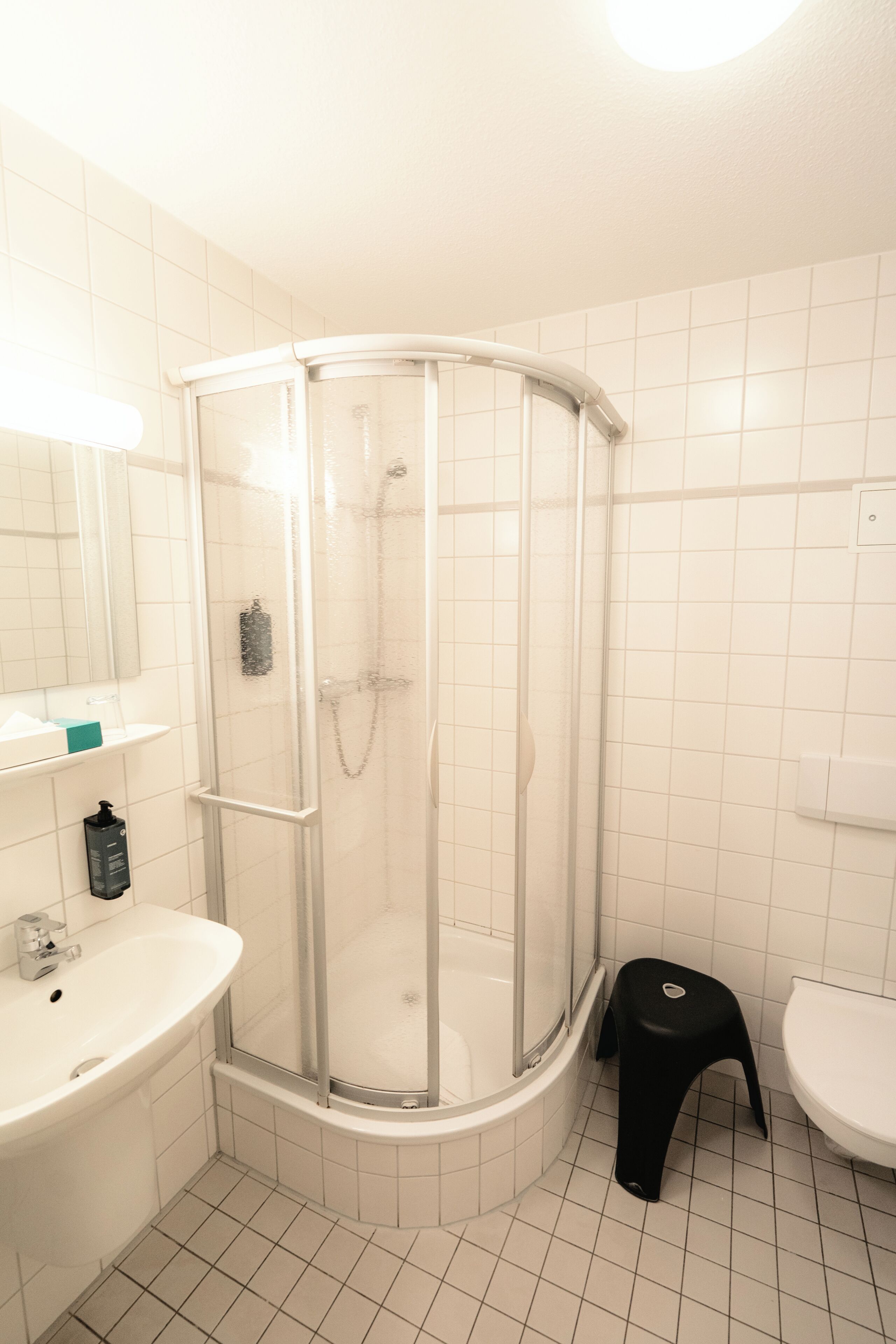 Un baño con ducha de vidrio, lavamanos e inodoro.