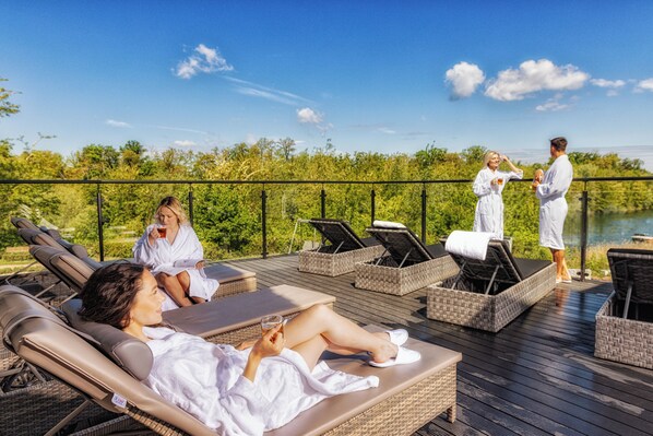 Una terraza con tumbonas, piscina y vistas al lago.