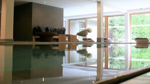 Un área de piscina interior moderna con vistas despejadas a la vegetación circundante a través de amplias ventanas.