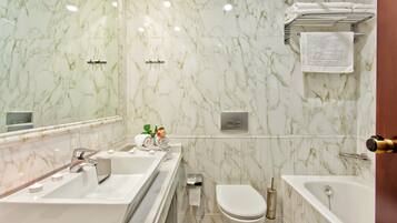 A bathroom with a marble wall, a sink, a toilet, and a bathtub.