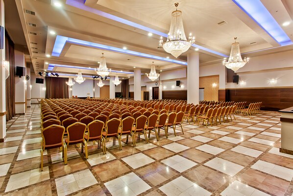 A spacious hall with rows of chairs and chandeliers. - Kouros Hotel (Drama)