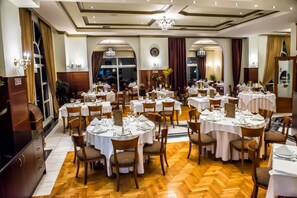 Un comedor formal con mesas redondas, sillas y candelabros.