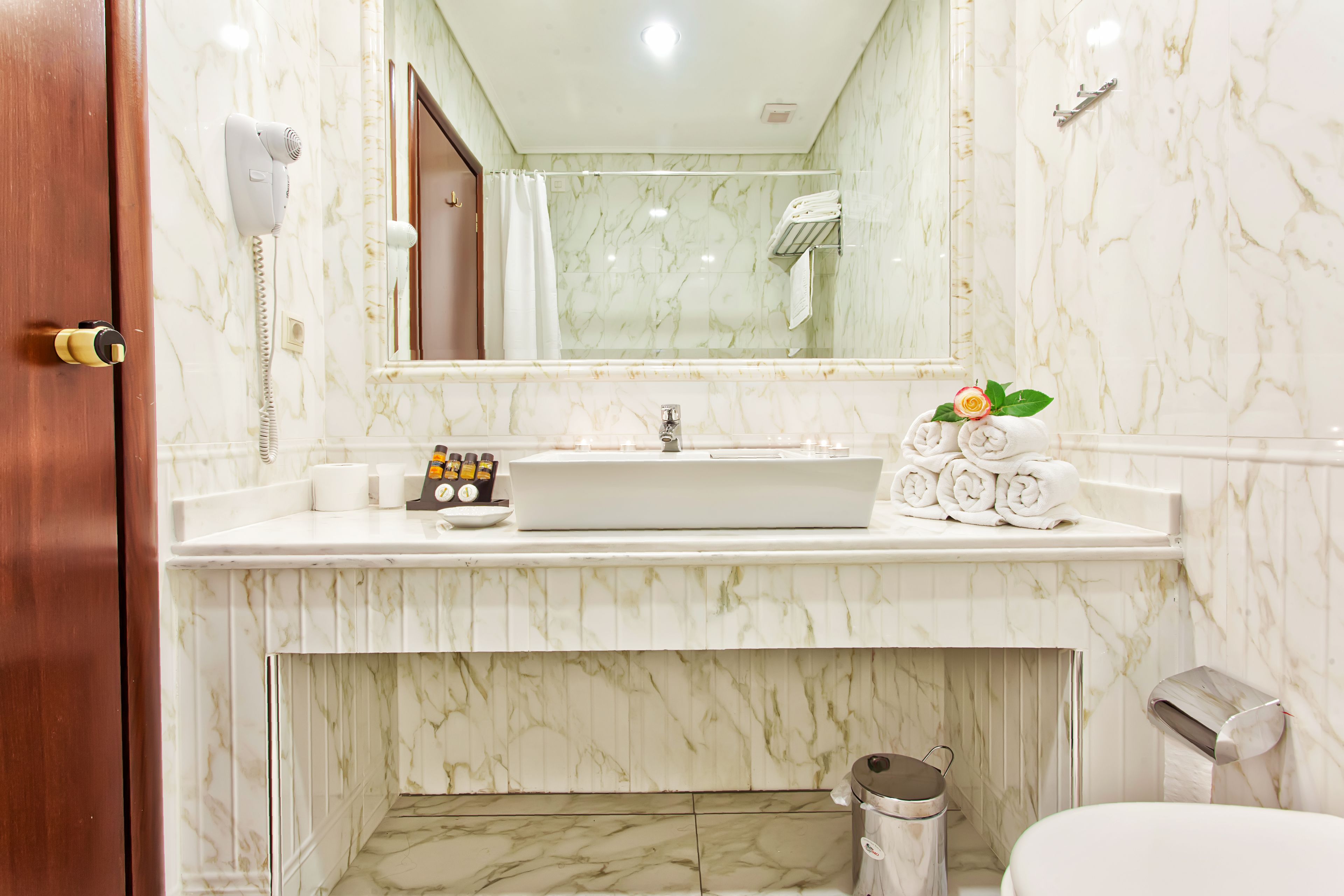 A bathroom with a marble sink, a hairdryer, and a towel rack.