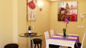 A dining area with a glass table, two black stools, a white tablecloth, and a vase with a purple flower. - La Volpe Rossa (Las Palmas de Gran Canaria)