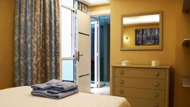 A hotel room with a bed, a dresser, a painting on the wall, and a door leading to a balcony. - La Volpe Rossa (Las Palmas de Gran Canaria)