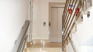 A clean, modern staircase with a handrail, leading to an elevator. - La Volpe Rossa (Las Palmas de Gran Canaria)