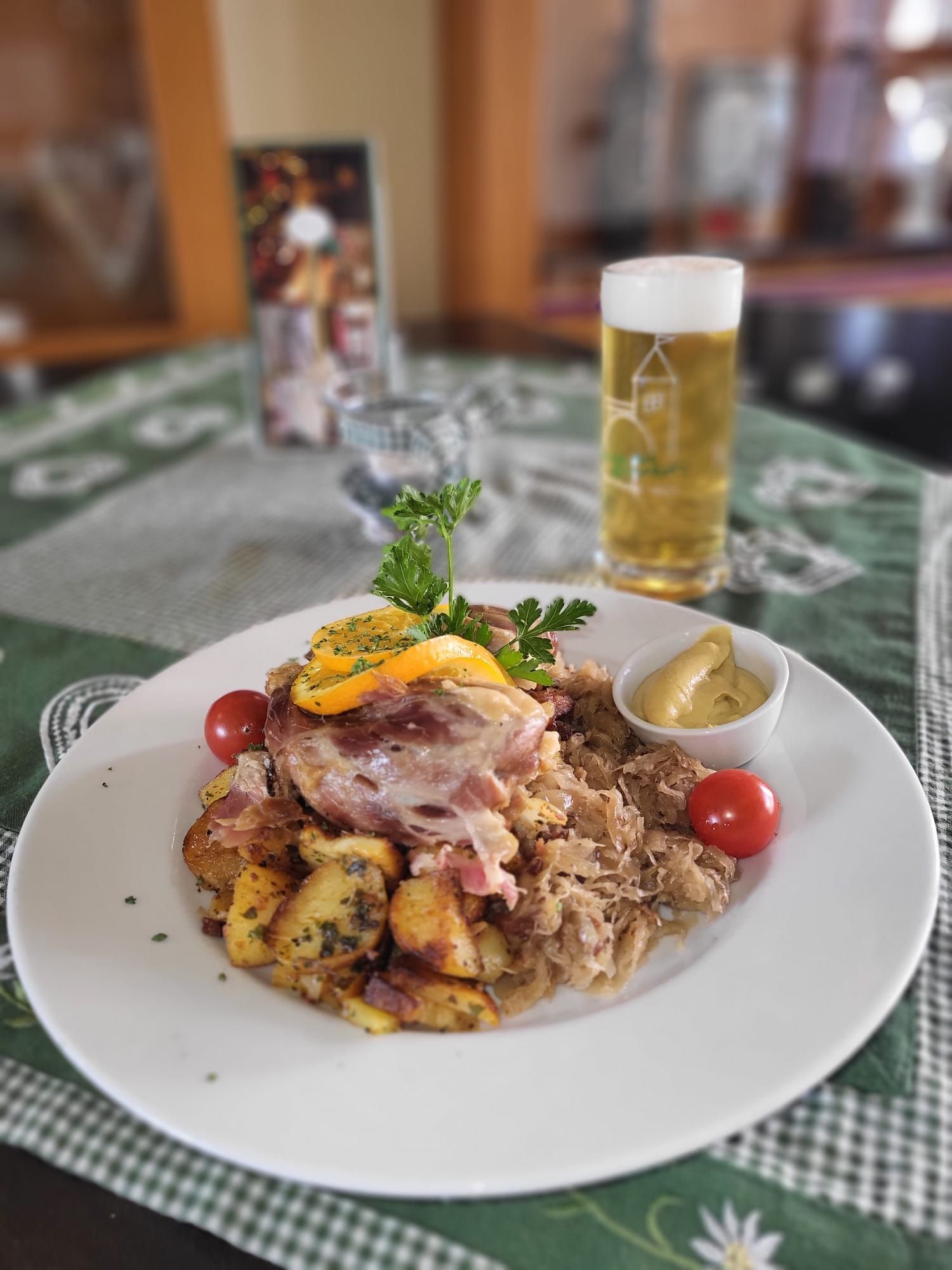 Un plato de comida con una jarra de cerveza sobre una mesa con mantel a cuadros.