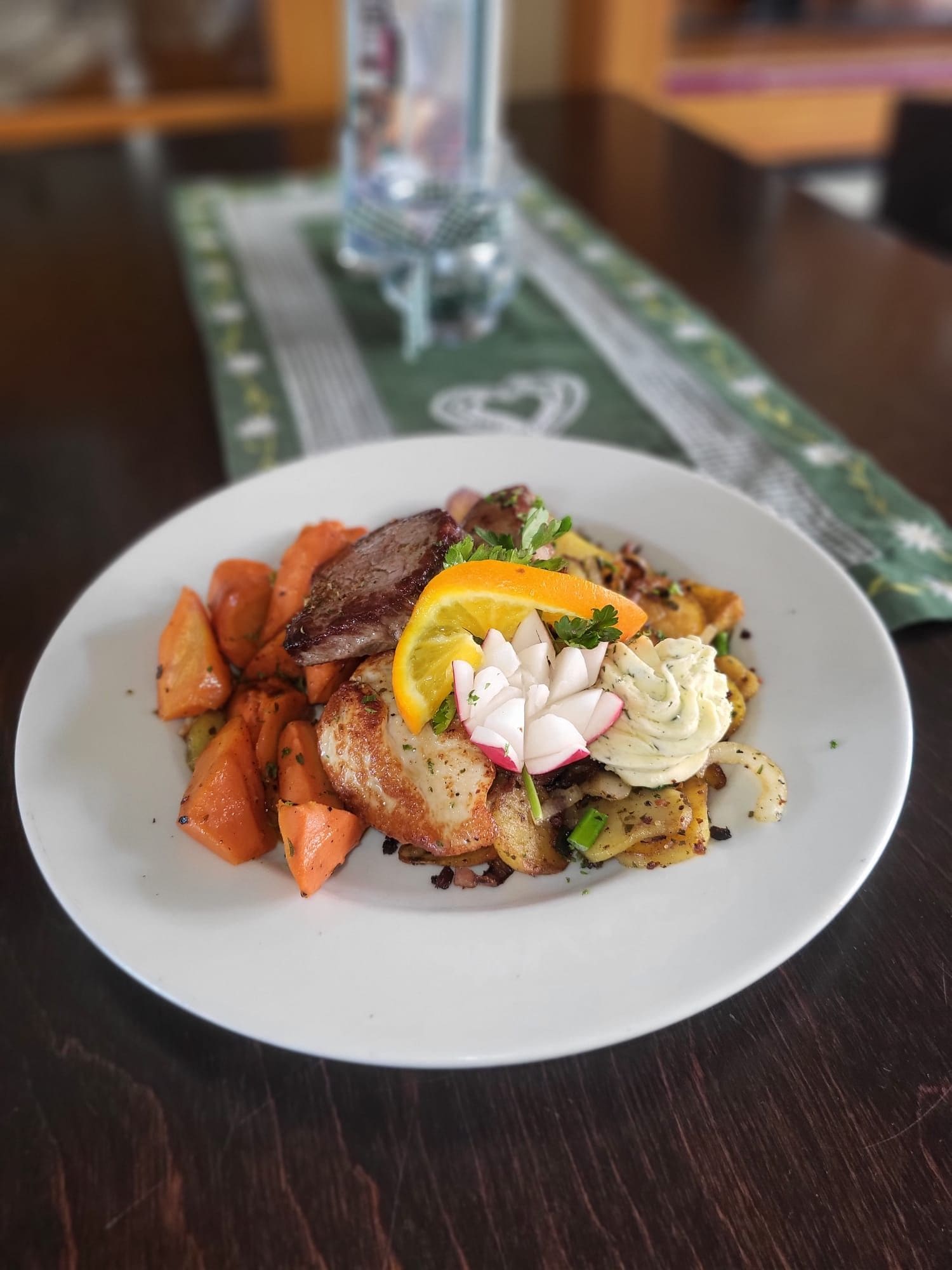 A plate of food with a piece of meat, roasted vegetables, and a garnish on a white plate.