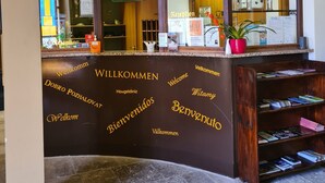 Een receptiebalie met meertalige borden en een glazen vitrine.