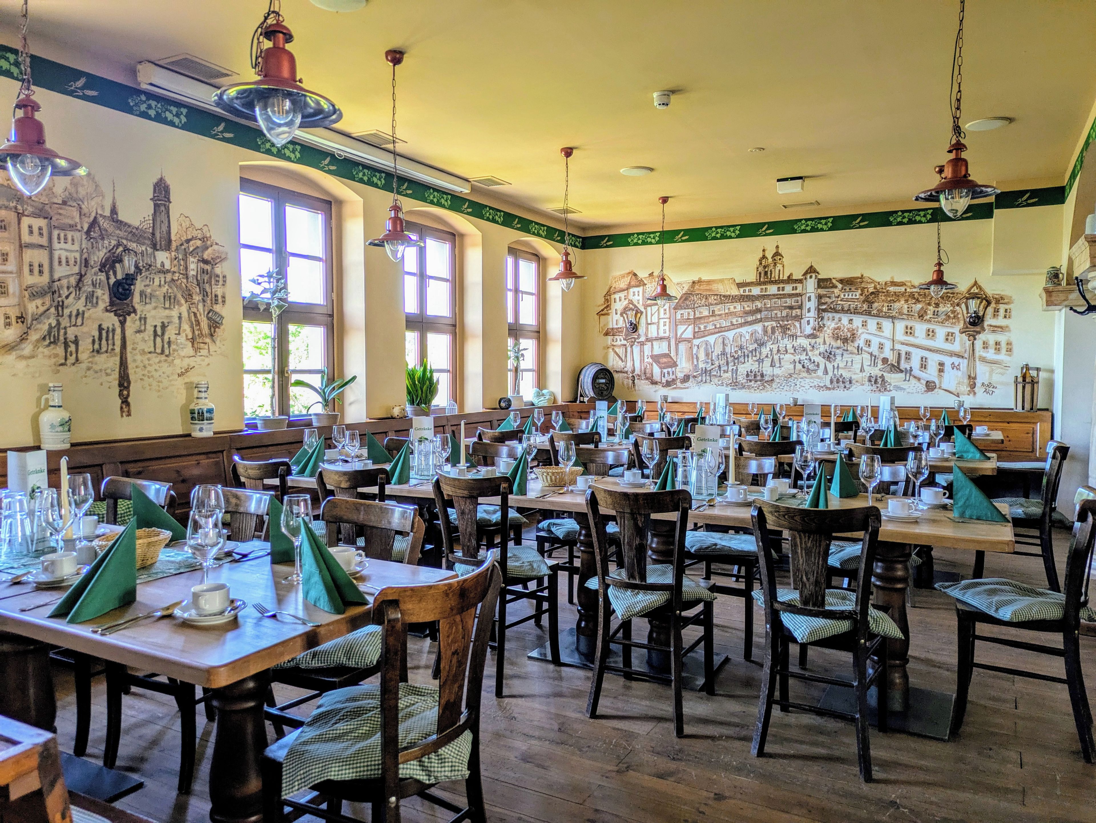 A restaurant with multiple tables, chairs, and hanging light fixtures.