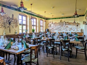 Un restaurante con varias mesas, sillas y lámparas colgantes.