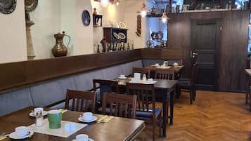 Ein Restaurant mit Holztischen und -stühlen, einem Fischgrätparkett und einer Kristallleuchter.