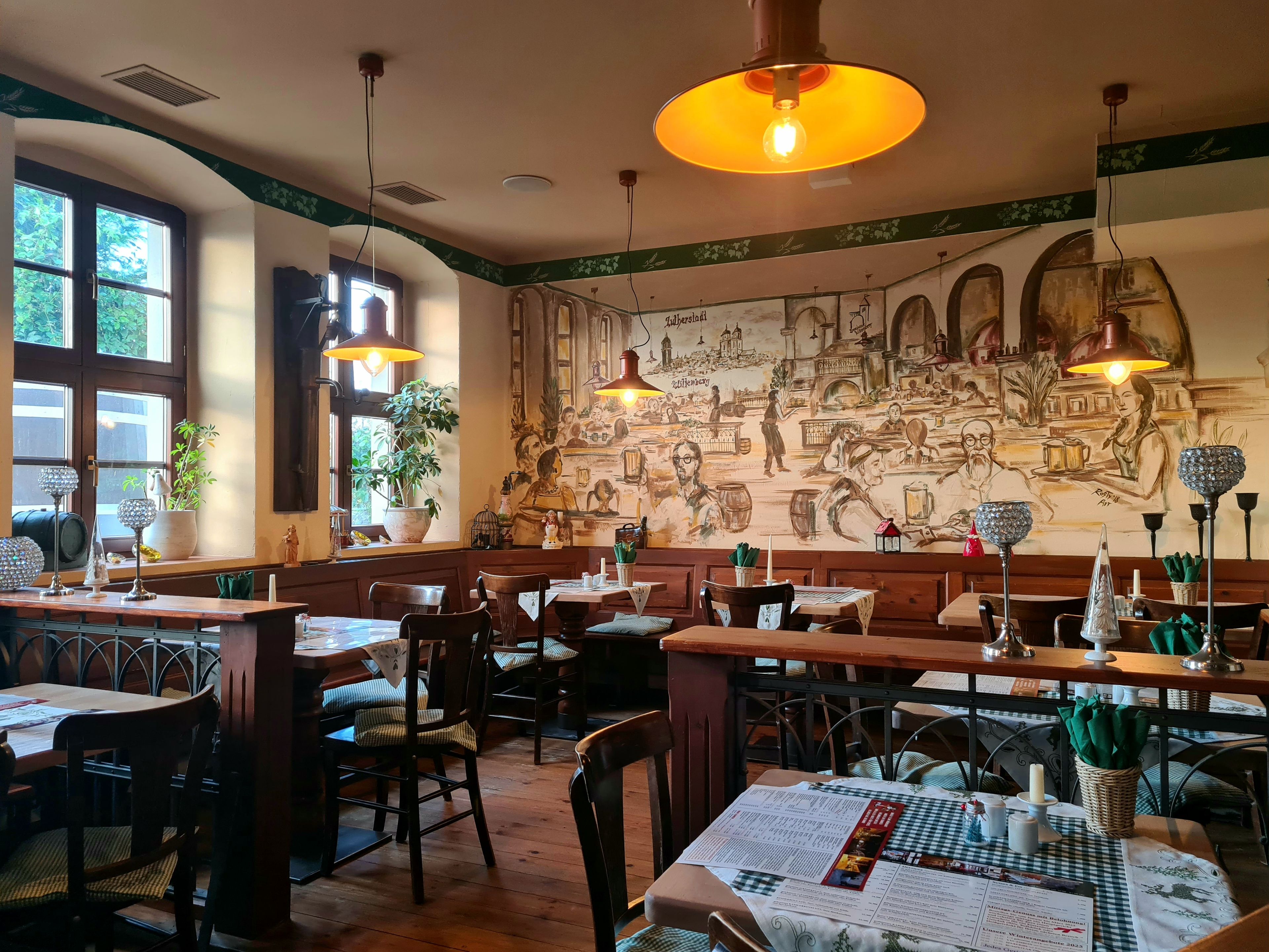 Ein Restaurantinneres mit Holztischen, Stühlen und einem Wandgemälde.
