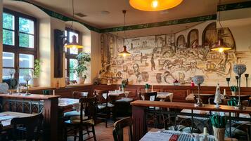 Ein Restaurantinneres mit Holztischen, Stühlen und einem Wandgemälde.