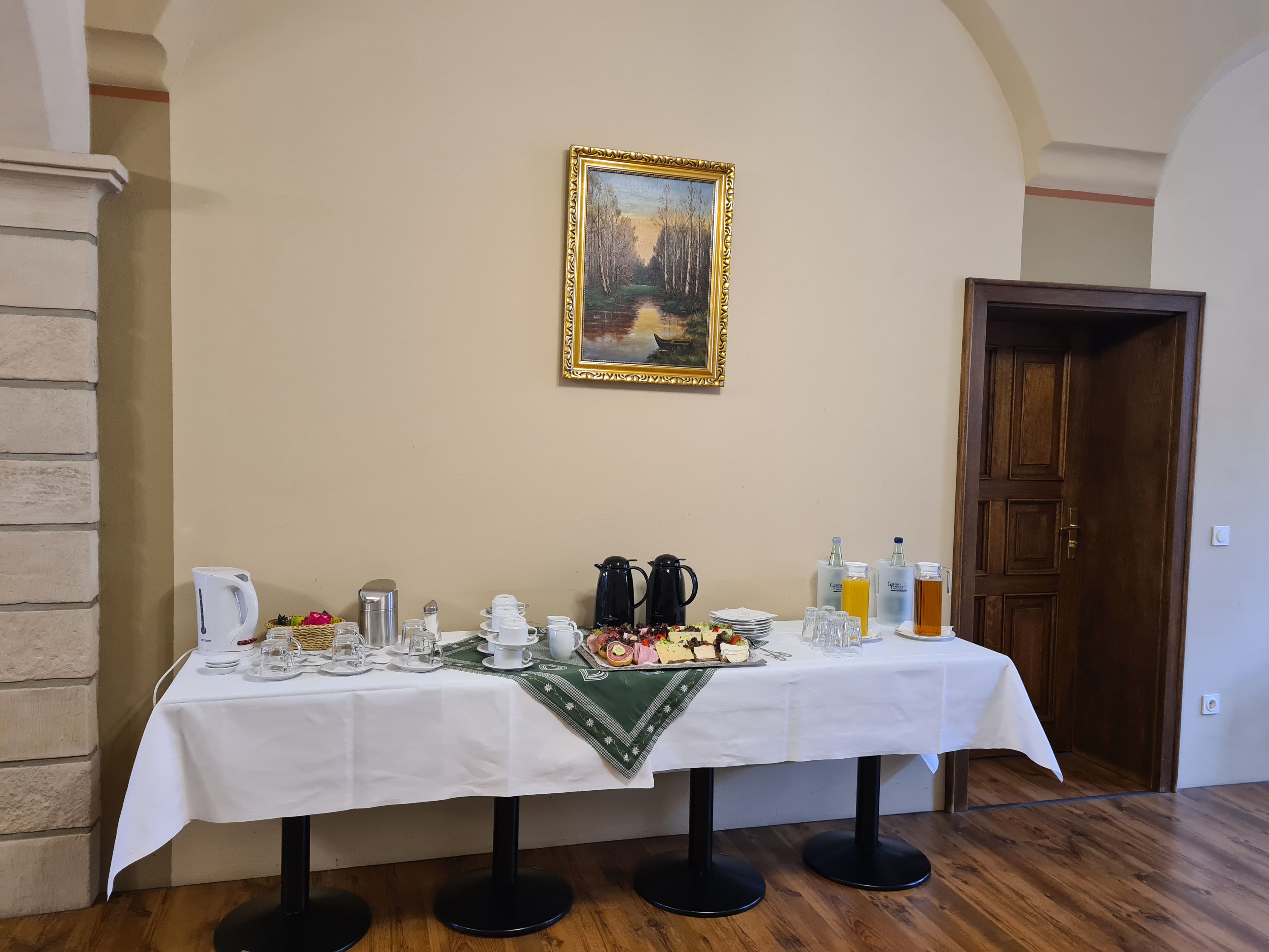 Une table à manger dressée avec divers aliments pour le petit-déjeuner, un tableau accroché au mur et une porte en bois.