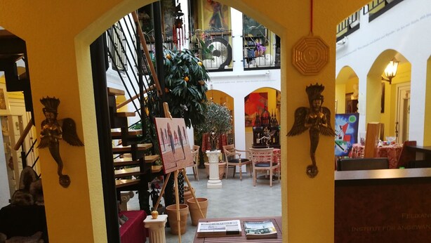 Vista interior de un edificio con una escalera, una mesa con revistas y un árbol de Navidad.