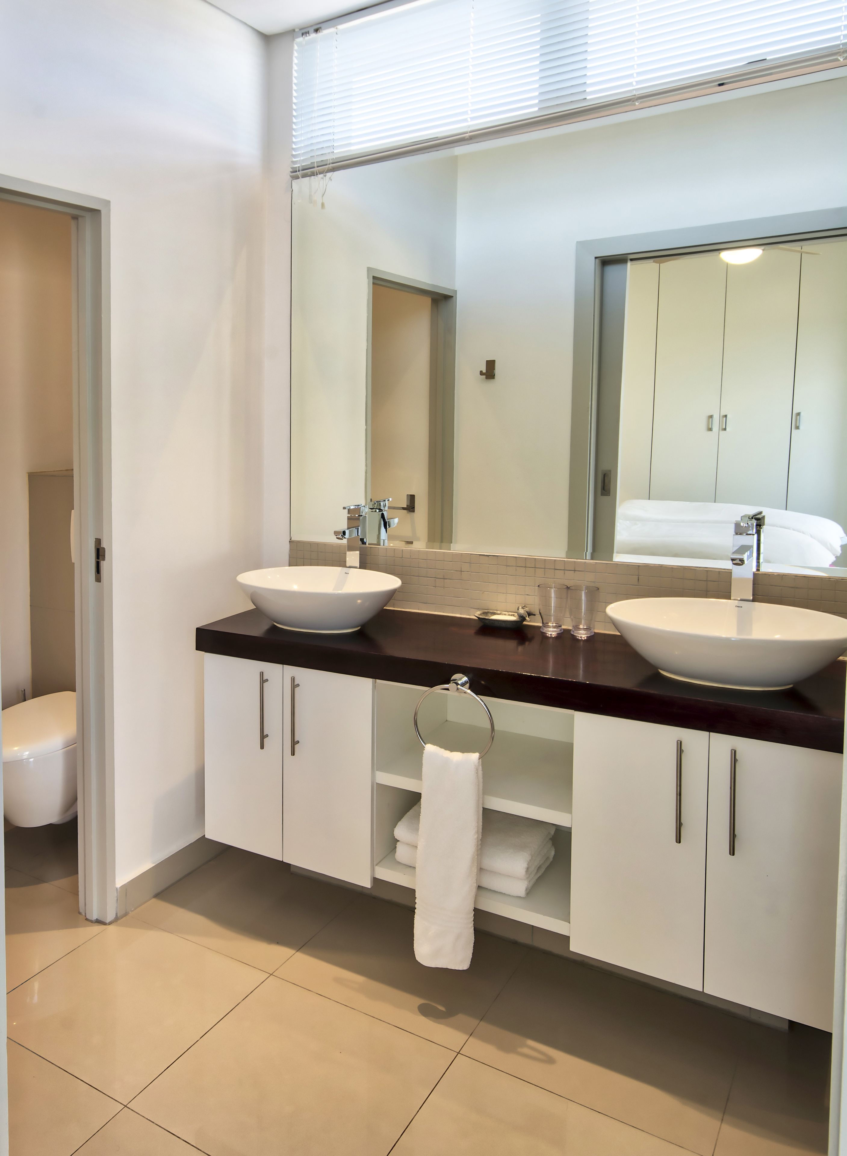 Ein modernes Badezimmer mit zwei Waschbecken, einem großen Spiegel und einer Toilette.