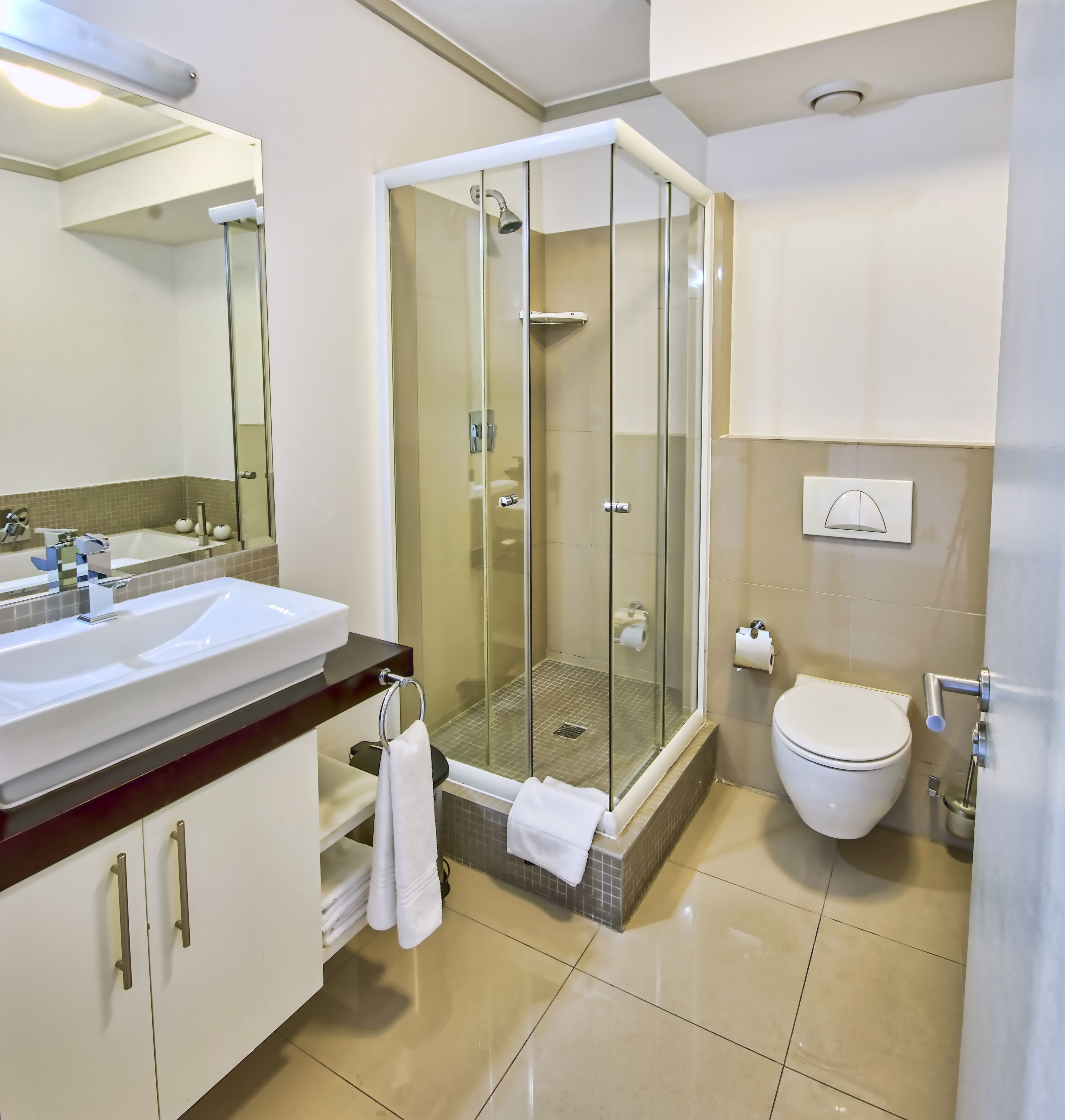 A modern bathroom with a glass-enclosed shower, a white sink, and a toilet.