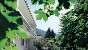 A building with a patio area featuring a table and chairs. - Private Holiday Homes by SOLARIA (Davos)