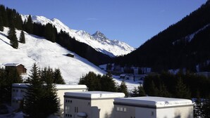 A snow-covered mountain landscape with a small village and buildings. - Private Holiday Homes by SOLARIA (Davos)
