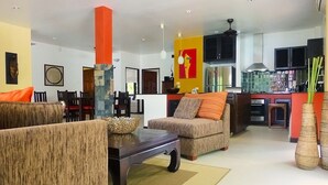 A modern living room with a sofa, a coffee table, and a dining area with chairs and a table. - Baan Lompai (Krabi)