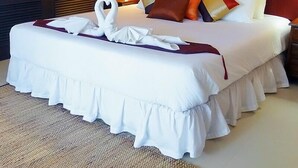 A hotel room with a large bed, a red accent wall, and a painting of bamboo. - Baan Lompai (Krabi)