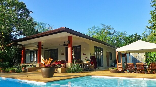 A poolside area with a covered patio, outdoor seating, and potted plants. - Baan Lompai (Krabi)