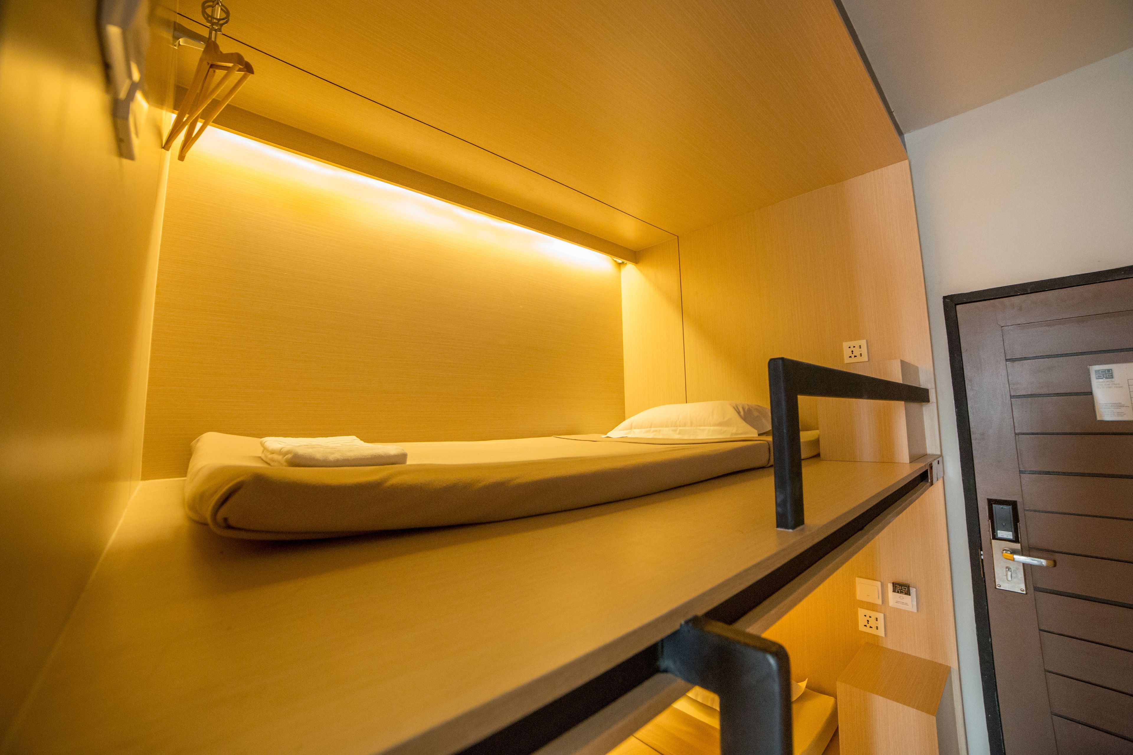 A bunk bed with a headboard and a bedside table, a wall socket, and a door with a handle.
