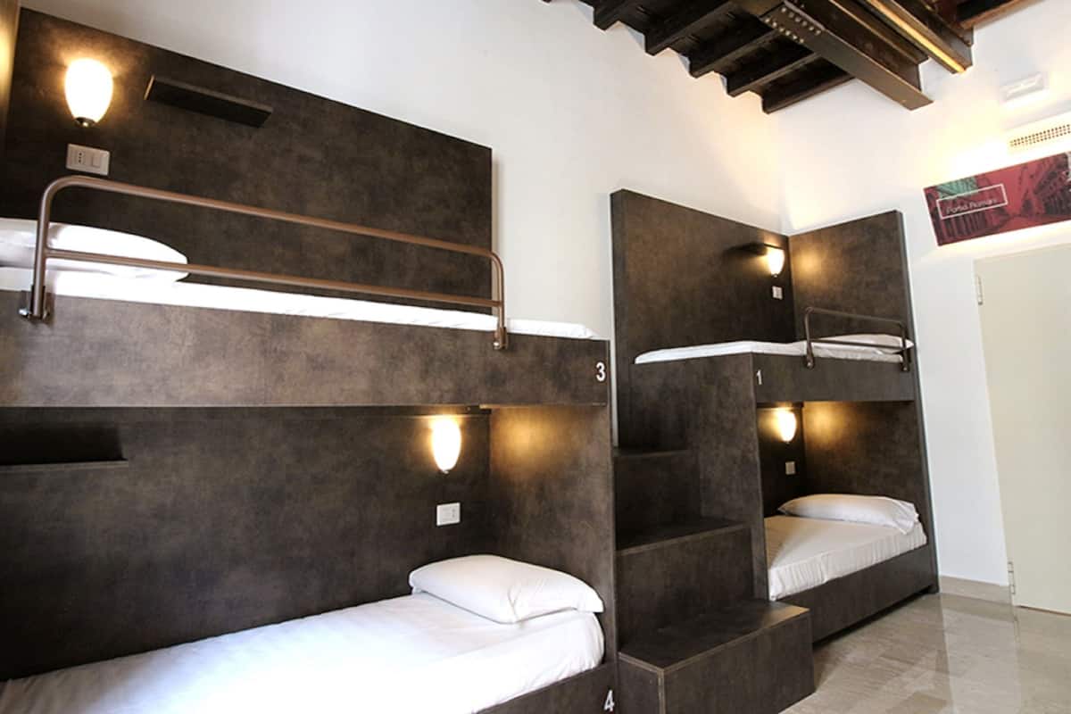 A room with bunk beds, each with a headboard and a light fixture above.