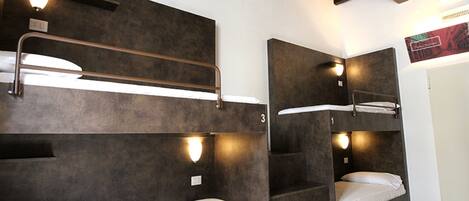 A room with bunk beds, each with a headboard and a light fixture above.