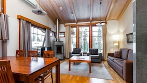 A spacious living area with a wooden dining table, sofas, and a fireplace. - Imatran Kylpylä Spa Apartments (Imatra)