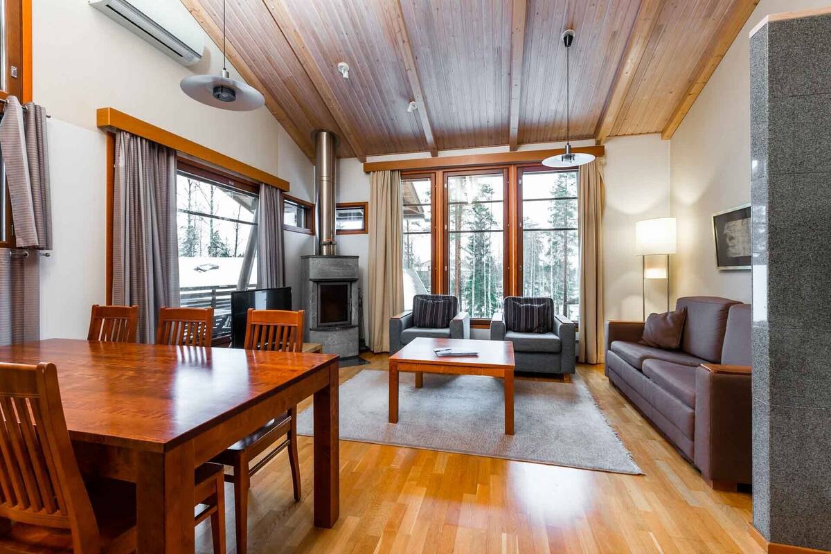 A spacious living area with a wooden dining table, sofas, and a fireplace.